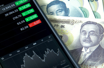 Japanese money, bills and smartphone, mobile trading on the stock exchange.