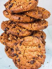 Chocolate chip cookies on white background. Stacked chocolate chip cookies on brown napkin. Symbolic image with place for text. Freshly baked. Concept for a tasty snack. Sweet dessert