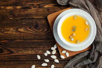 Bowl of pumpkin soup on rustic wooden background