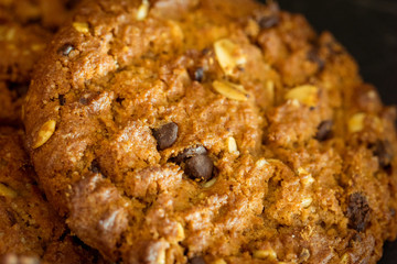Chocolate chip cookies on rustic dark black background. Stacked chocolate chip cookies on brown napkin. Symbolic image with place for text. Freshly baked. Concept for a tasty snack. Sweet dessert