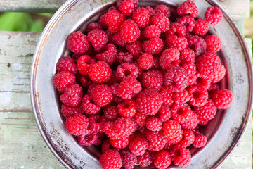 fresh harvest raspberries in metal plate on the wooden table
