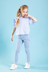 Full-length portrait of a beautiful girl in blue clothes on a blue background.