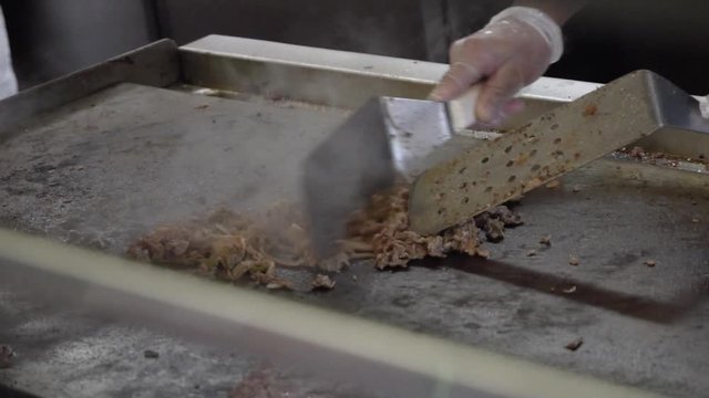 Chopping a cheese steak on a griddle, in slow motion