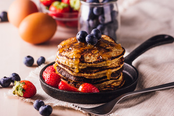 Stack of homemade pancakes with blueberries and strawberries, perfect for breakfast
