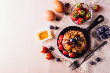 Stack of homemade pancakes with blueberries and strawberries, perfect for breakfast