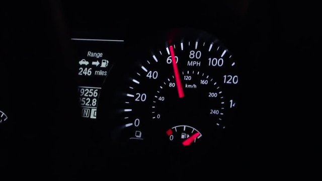 Speedometer reading around 60 miles an hour inside a car at night