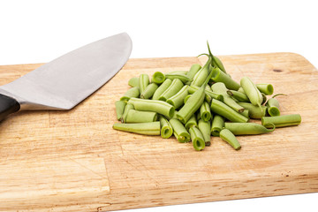 Fresh green beans on a cutting board on a table, white isolated background