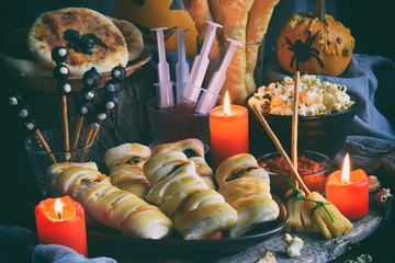 Halloween trick or treat party. Funny delicious food and pumpkin on wooden background - mini pizza,...
