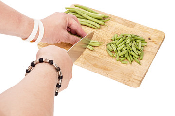 Slicing fresh green beans on a cutting board on a table, white isolated background