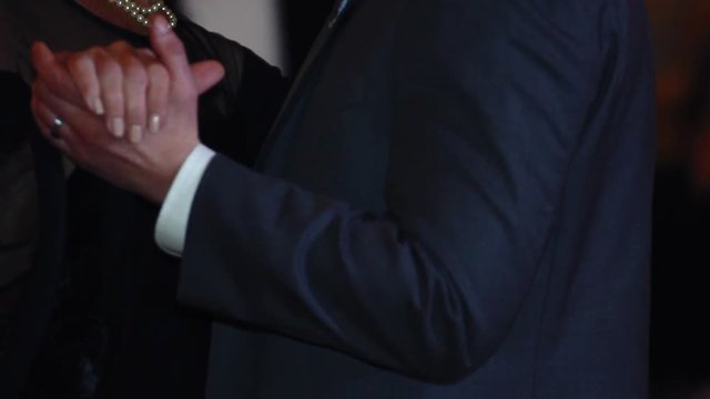 Close up of hands as a mother and son slow dance on his wedding day, in slow motion