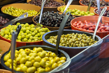 Bowls of green and black olives on display on a market stall