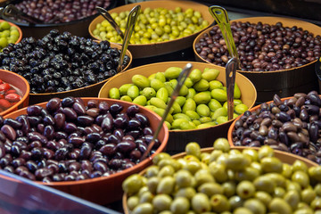 Bowls of green and black olives on display on a market stall