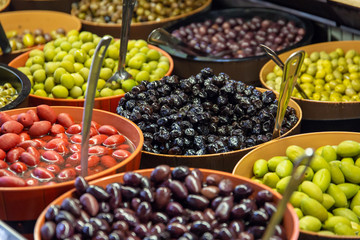 Bowls of green and black olives on display on a market stall