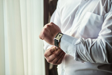 Obraz na płótnie Canvas businessman checking time on his wrist watch, man putting clock on hand,groom getting ready in the morning before wedding ceremony