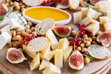Light Italian snacks. A buffet table at a dinner party. Cheese plate. Delicious cheese mix on wooden table. Tasting dish on a wooden plate. Food for wine.