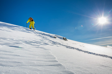 High altitude mountain explorer walking through deep snow in high mountains on a freezing winter day