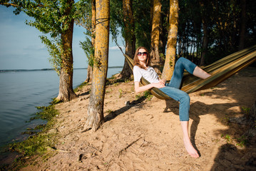 Woman relaxing in a hammock on the beach, a hot sunny day