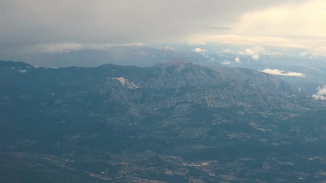 Aerial View. Flying over the high mountains in beautiful clouds