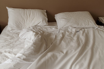 Unmade white mattress and pillows on a bed