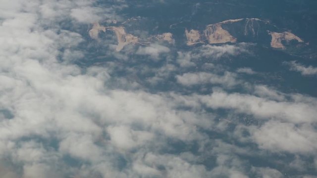 Aerial View. Flying over the high mountains in beautiful clouds