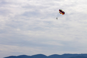 в облачном небе летит цветной парашют