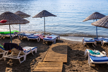 An empty beach in a heavenly bay. Beach umbrellas with sunbeds and towels on towels. Sea and sky...