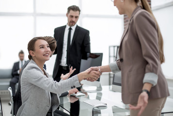 handshake two business women near the desktop
