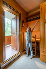 Fototapeta premium Cute little girl opening big glass sliding door to the balcony