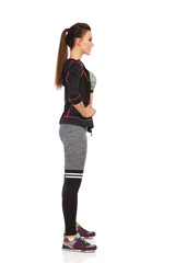 Beautiful Young Woman In Sports Clothes Is Standing With Hand On Hip. Side View.