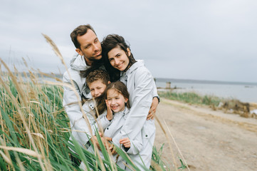 Beautiful family portrait dressed in raincoat near the lake