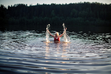 Elderly woman swimming in the summer river.