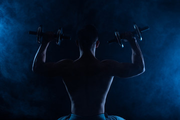 Fototapeta na wymiar Muscular silhouette of man, with blue smoke on background