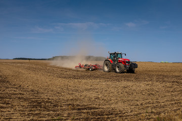 Roter Traktor pflügt Feld im Spätsommer