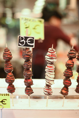 Strawberries on a stick covered in chocolate at the market