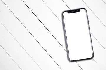 Smartphone lies on a wooden table. Isolated white screen with copy space.