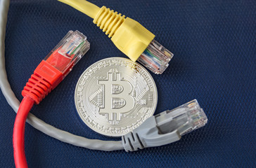 Metal coin of bitcoin with color ethernet plugs around