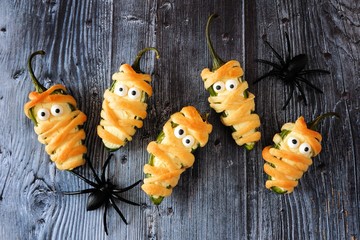 Fun Halloween mummy jalapeno poppers, top view on rustic old wood background