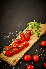 delicious and juicy cherry tomatoes and basil on a wooden board on a black table