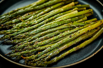 delicious and juicy green asparagus in a pan on an old wooden black table