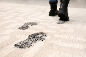 Person in dirty shoes leaving muddy footprints on carpet