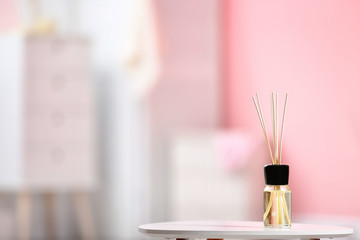 Aromatic reed air freshener on table against blurred background