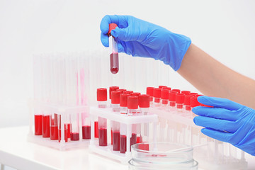 Scientist working with blood samples in test tubes at table