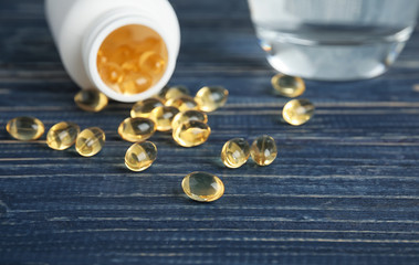 Cod liver oil pills and glass of water on table, closeup