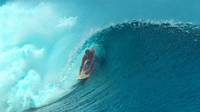 CLOSE UP: Large emerald ocean wave splashes over the cheerful extreme surfer.