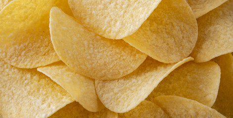 Golden crispy potato chips snack texture background shot. Close up. Banner. Horizontal.