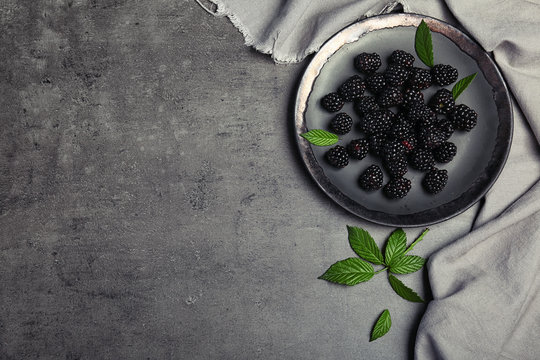 Flat lay composition with plate of fresh blackberry and space for text on gray background