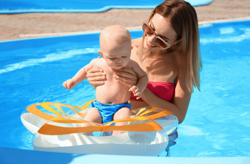 Fototapeta premium Happy mother with little baby in swimming pool on sunny day