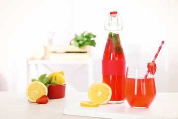 Bottle and glass with natural lemonade on table indoors