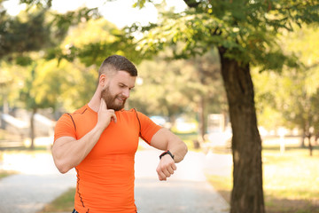 Young man checking pulse after workout in park