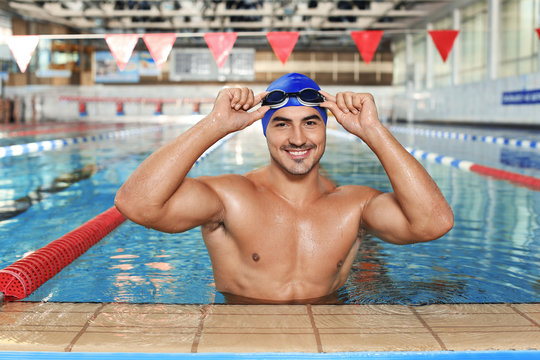 Young athletic man wearing cap and goggles in swimming pool